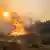 Sob o sol e um céu coberto pela fumaça, um homem tenta combater as chamas que queimam uma área verde na Ilha de Rhodos, na Grécia.