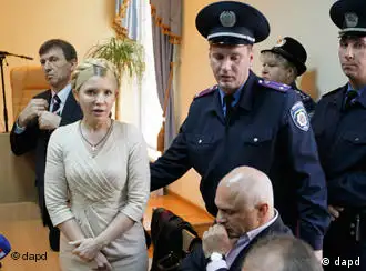 Julia Timoschenko es escoltada por un policía al salir de la corte.