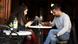 A man and a woman sit outside a coffee shop looking at their phones A man and a woman sit outside a coffee shop looking at their phones