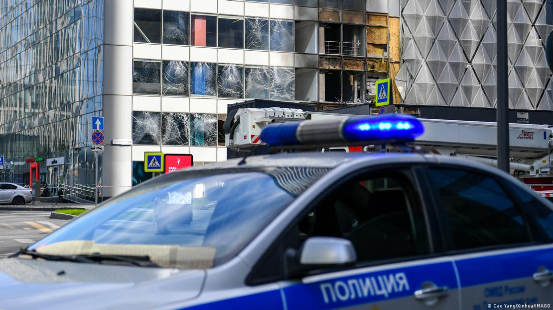 Em primeiro plano, uma viatura policial russa. Atr&aacute;s, um edif&iacute;cio espelhado com tr&ecirc;s andares de vidra&ccedil;as danificadas mostra dano causado por drone que explodiu no distrito empresarial de Moscou em 30 de julho.