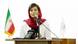 Elaheh Mohammadi fala ao microfone, sentada em mesa com bandeirinha do Irã Elaheh Mohammadi fala ao microfone, sentada em mesa com bandeirinha do Irã