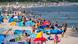 A beach filled with people and bright tents. A beach filled with people and bright tents.