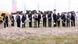  People, the men in suits, with shovels in a line