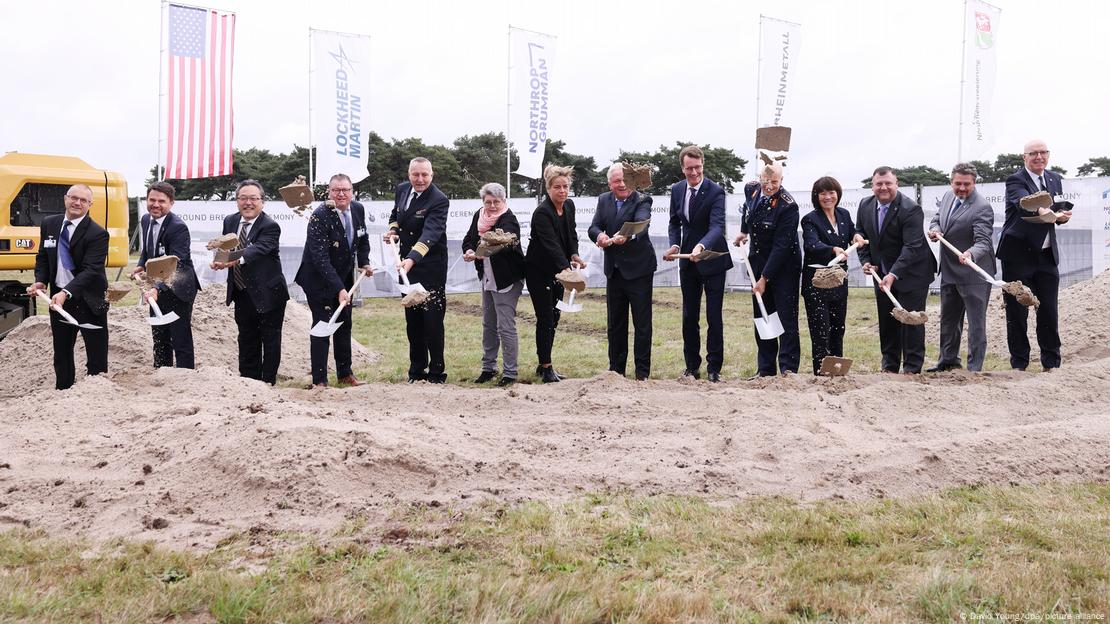  People, the men in suits, with shovels in a line