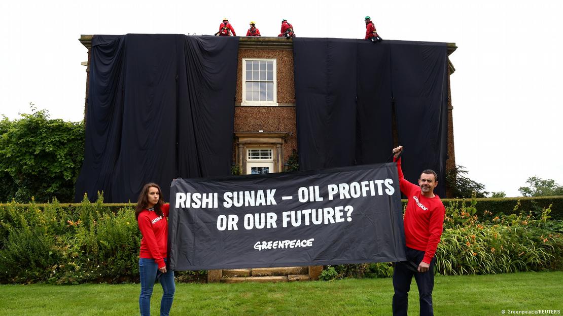 Greenpeace activists hold up a banner in front of Sunak's house saying "Rishi Sunak — oil profits or our future?"