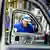 Um trabalhador uniformizado em uma montadora de carros é emoldurado pela porta de um carro.