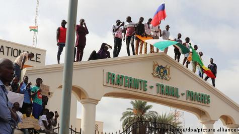 Başkent Niamey'de, ellerinde bayraklarla, bir araçkapısı üstüne çıkmış halde darbecilere destek veren Nijerliler - (03.08.2023)