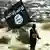 یکی از اعضای گروه تروریستی داعش در حال حمل پرچم این گروه 