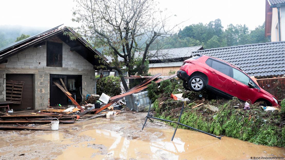 Casa destruida e carro jogado sobre canteiro, danos causados pela enchente em vilarejo na Eslovênia