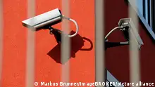 Überwachungskamera hinter Zaun, Symbolbild für Überwachungsstaat