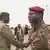 A Niger junta member greeting Burkinabe military delegates on the tarmac of a Niamey airport. 