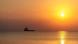 Sun setting on the sea. A silhouette of a boat in the background Sun setting on the sea. A silhouette of a boat in the background