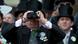 A spectator wearing a cylinder hat watches a horse race through his binoculars A spectator wearing a cylinder hat watches a horse race through his binoculars