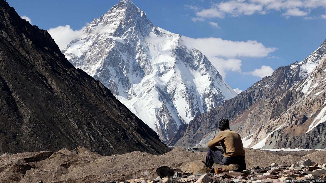 Se ve a una persona sentada con la segunda montaña más alta del mundo de fondo.