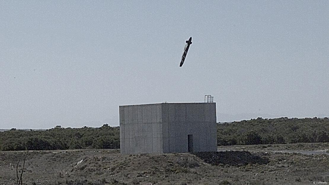 Ein Geschoss kurz vor dem Einschlag von oben in einen Betonbunker