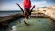 A young man in red swimming trunks flips into a swimming pool on the coast A young man in red swimming trunks flips into a swimming pool on the coast