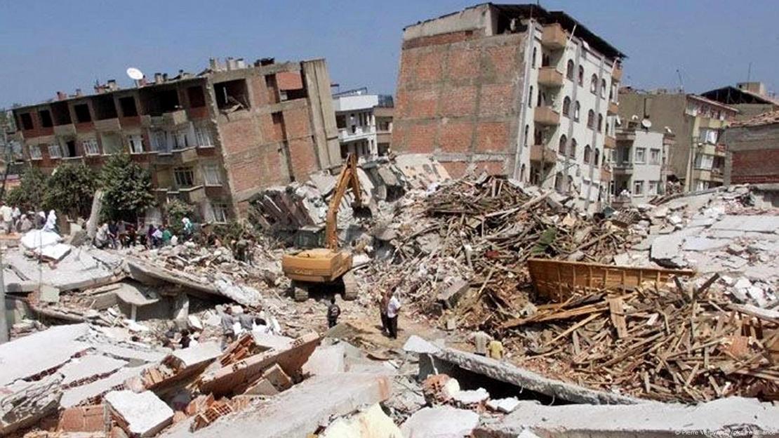 17 Ağustos 1999 tarihinde meydana gelen depremde Adapazarı'nda yerle bir olmuş binalar. Enkaz yığını üzerinde çalışan bir iş makinesi görülüyor