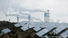 FILE PHOTO: Smoke rises from chimneys near solar panels, during a Huawei-organised media tour, in Shaanxi province, China April 24, 2023. REUTERS/Tingshu Wang/File Photo