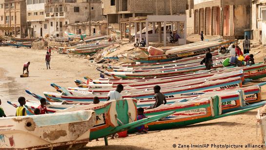 Children play on fishing boats known as "pirogues" on a beach in Dakar