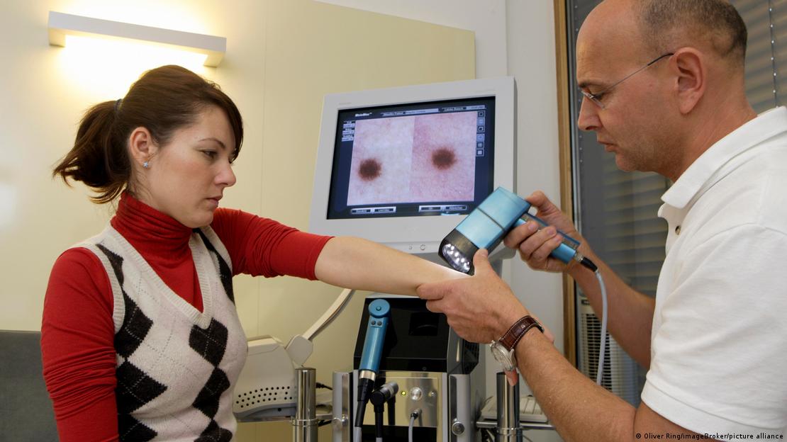 Un dermatólogo examina a una paciente mediante videodermatoscopía.