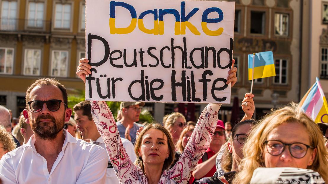 Eine Gruppe von ukrainischen Flüchtlingen. Eine Frau hält ein Transparent hoch auf dem geschrieben steht: "Danke Deutschland für die Hilfe"