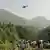 eople watch as an army soldier slings down from a helicopter during a rescue mission to recover students stuck in a chairlift in Pashto village of mountainous Khyber Pakhtunkhwa province