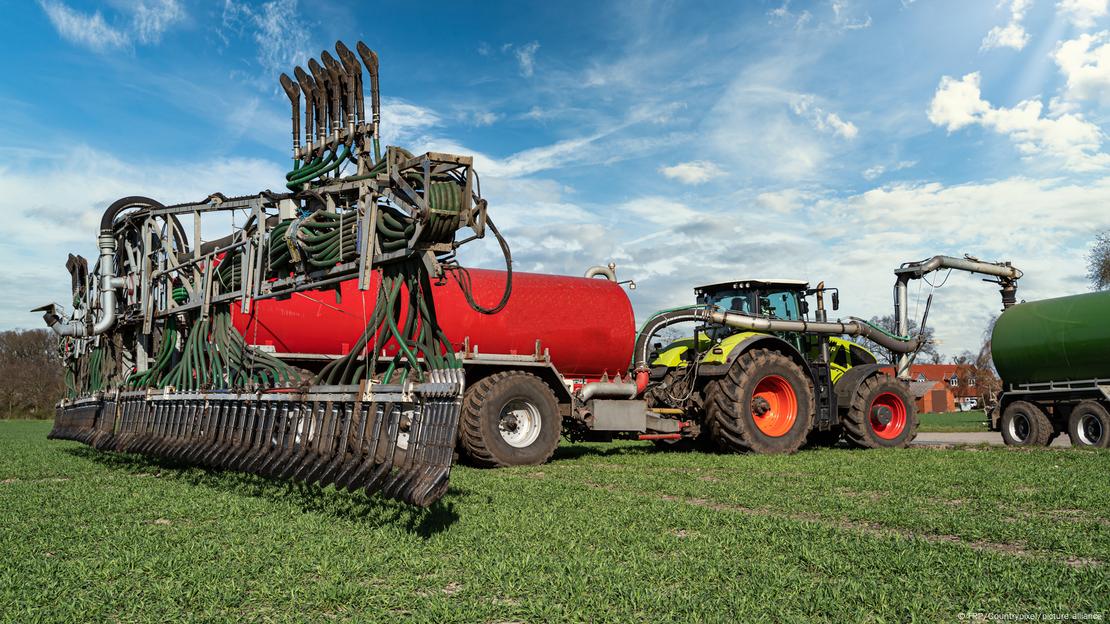 Un gran tractor esparce fertilizante nitrogenado en un campo. Un gran tractor esparce fertilizante nitrogenado en un campo.