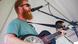 Ein Mann mit Gitarre und Sonnenbrille singt in ein Mikrofon Ein Mann mit Gitarre und Sonnenbrille singt in ein Mikrofon