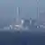 Imagen de un puerto, con la planta de Fukushima al fondo.