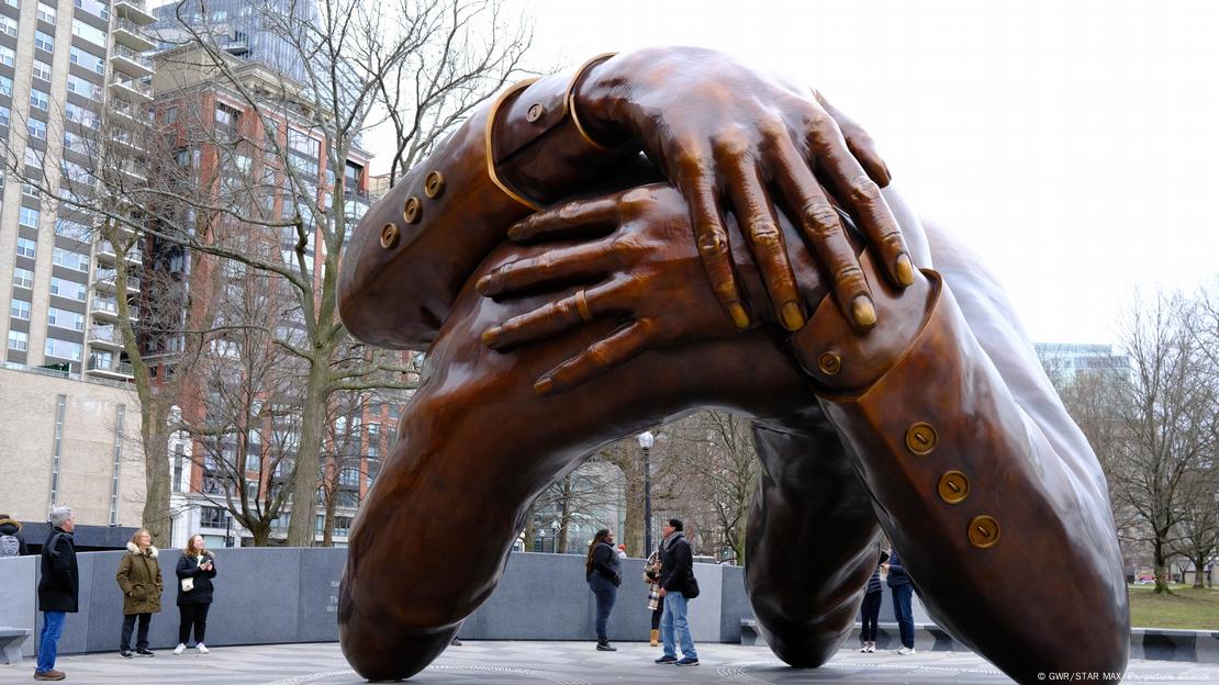 Enorme estátua em bronze, em que braços se entrelaçam