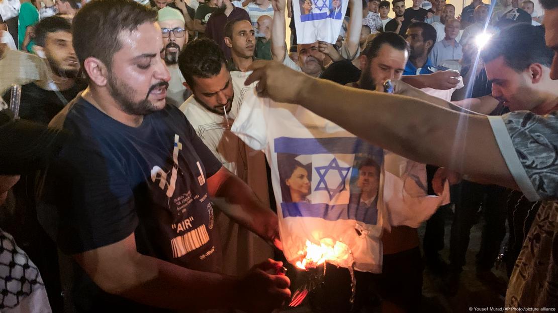 Bei anti-Israelischen Protesten in Tripolis zündet ein Mann ein T-Shirt an, auf dem Abbildungen von Nadschla al-Mankusch und Eli Cohen zu sehen sind