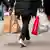 Um consumidor carrega quatro sacolas de estabelecimentos comerciais na rua de uma cidade da Alemanha.