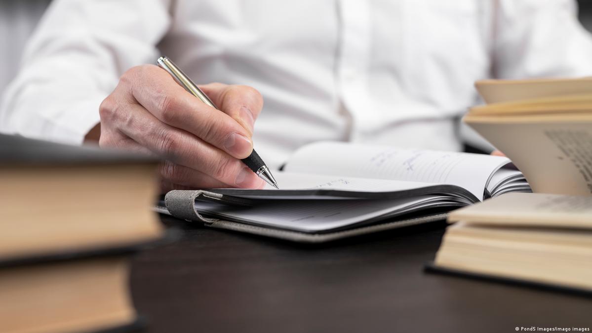 Man sitting at desk at home or in office and studying, searching and analyzing information in books or codes