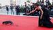 A woman in a black gown reaching out to her dog on the red carpet A woman in a black gown reaching out to her dog on the red carpet