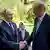 Putin dhe Erdogan në Soçi duke i dhënë dorën njëri-tjetrit. Putini e shikon me buzëshje Erdognin, ndërsa ky duket më serioz. Në sfond gjelbërim dhe dy roje. Ndërsa pranë Putinit është një perkthyese.
