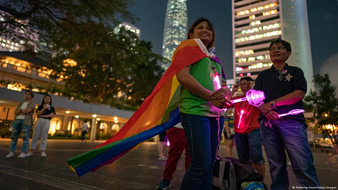 Aliados y miembros de la comunidad LGBT celebran en Hong Kong, con bastones luminosos rosas y banderas de la diversidad.