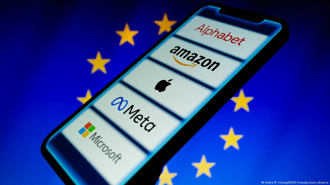 Avrupa Birliği bayrağının üzerinde duran bir akıllı telefon ekranında Meta, Apple, Amazon, Microsoft ve diğer büyük teknoloji şirketlerinin logoları yer alıyor.