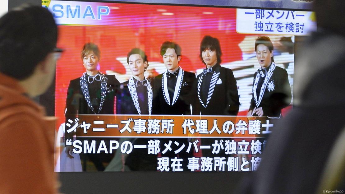 Pantalla muestra componentes de SMAP, grupo musical japonés. Rótulos en japonés en la parte inferior de la pantalla.