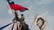 Homem empunha bandeira chilena em cima de uma estátua. Ao lado, uma imagem de Víctor Jara. Homem empunha bandeira chilena em cima de uma estátua. Ao lado, uma imagem de Víctor Jara.