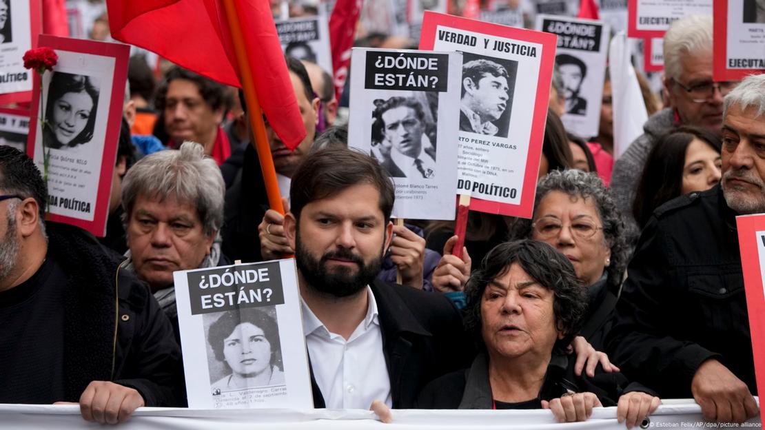 Presidente do Chile, Gabriel Boric, em meio a manifestantes que seguram cartazes de busca por desaparecidos políticos durante a época do regime militar no país, entre os anos 70 e 90.