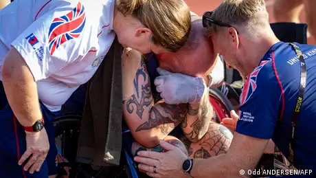 A British athlete is comforted after his race. 