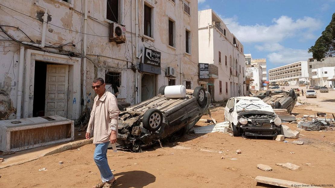 Un hombre camina delante de coches dañados, después de que una fuerte tormenta y lluvias torrenciales azotaran Libia, en Derna, Libia.