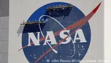 ARCHIV - 20.05.2020, USA, Cape Canaveral: Arbeiter auf einem Gerüst streichen das Nasa-Logo in der Nähe des Fahrzeugmontagegebäudes im Kennedy Space Center. Die US-Raumfahrtbehörde Nasa will am 14.09.2023 einen neuen Bericht zu «nicht identifizierten ungewöhnlichen Phänomenen» veröffentlichen. Foto: John Raoux/AP +++ dpa-Bildfunk +++
