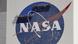 El logo de la NASA sobre una pared con trabajadores pintando la imagen.