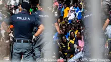 14.9.2023 ** TOPSHOT - Migrants gather outside the operational center called Hotspot on the Italian island of Lampedusa on September 14, 2023. The tiny Italian island of Lampedusa struggled on September 14, 2023 to cope with a surge in migrant boats from North Africa after numbers peaked at 7,000 people -- equivalent to the entire local population. (Photo by Alessandro Serranò / AFP) (Photo by ALESSANDRO SERRANO/AFP via Getty Images)