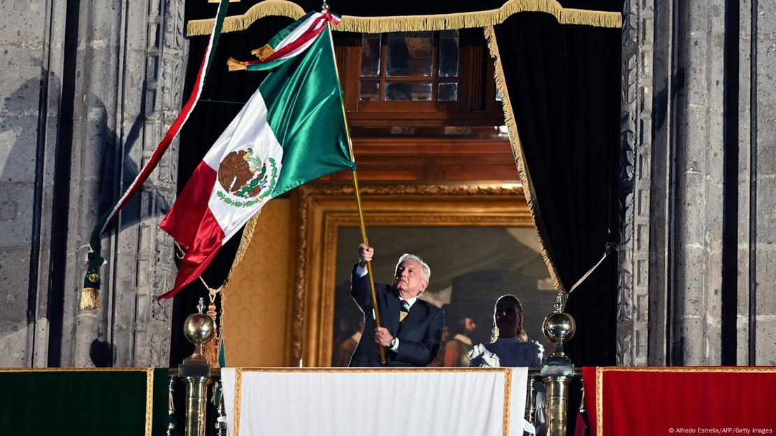 López Obrador enarbola la bandera mexicana desde el balcón del palacio presidencial anoche durante el tradicional Grito de Independencia.