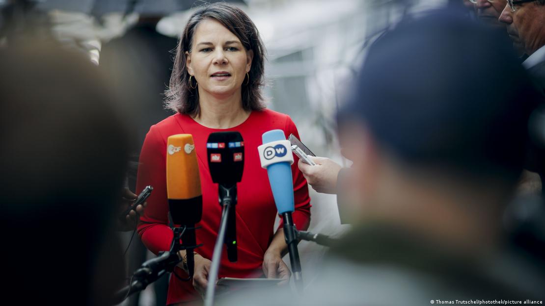 Ministrja e Jashtme gjermane, Annalena Baerbock veshur em fustan të kuq duke folur para mikrofonëve