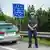 Un agente de la Policía fronteriza bávara junto a su coche y un poste de señalización en la frontera.