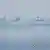 Tres embarcaciones se observan frente a una hilera de boyas blancas que flotan en el mar. La Guardia Costera filipina dijo haber retirado una "barrera flotante" colocada por Pekín en el mar de China Meridional.
