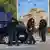 Katër policë të Kosovës të armatosur duke kontrolluar një makinë që po kalon pranë manastirit